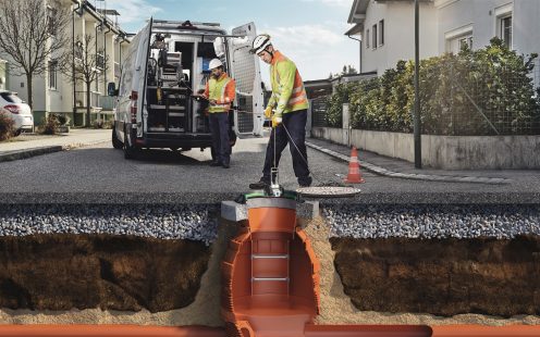 Two plumbers are carrying out a wastewater system inspection in a residential area.