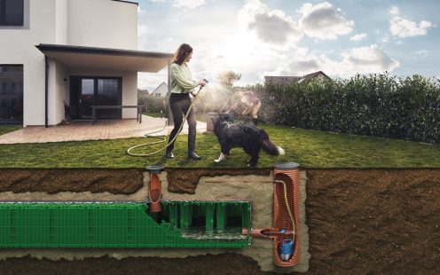 Reveal of rainwater attenuation system in garden with woman and a dog
